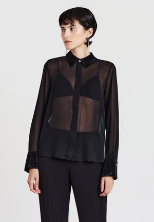 Schwarze durchscheinende Bluse mit Kragen, Knopfleiste und langen Ärmeln mit Samtbündchen. Texturierter Stoff mit leichter Transparenz.