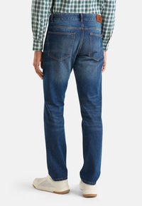 Blauwe denim jeans met een recht design, bruin leren patch op de tailleband en zichtbare achterzakken. Draag ze met lichte sneakers.