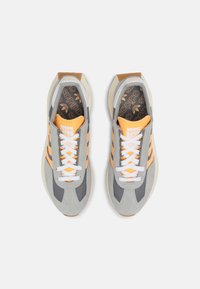 Scarpe da atletica grigie e arancioni realizzate in materiali scamosciati e in rete, con lacci bianchi, tre strisce arancioni e una soletta nera a motivo.