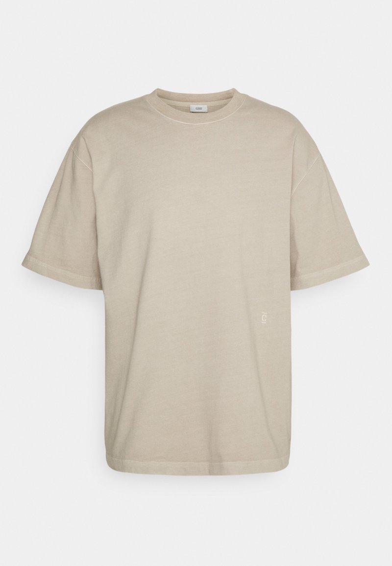 T-shirt en coton beige à coupe décontractée, col rond et manches courtes. Présente un logo discret près de l'ourlet.
