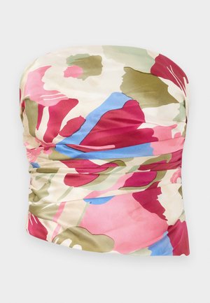 Top tanpa tali dengan desain berkerut, terbuat dari kain halus dalam nuansa merah muda, hijau, dan biru dengan latar belakang krim terang.