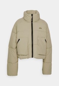 Cropped puffer jacket in beige, featuring a high collar, front zipper, and two large front pockets with a quilted texture.