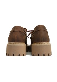 Brązowe skórzane buty o zaokrąglonym kształcie, z grubą jasnobrązową gumową podeszwą z wyżłobionymi detalami i wiązaniem.