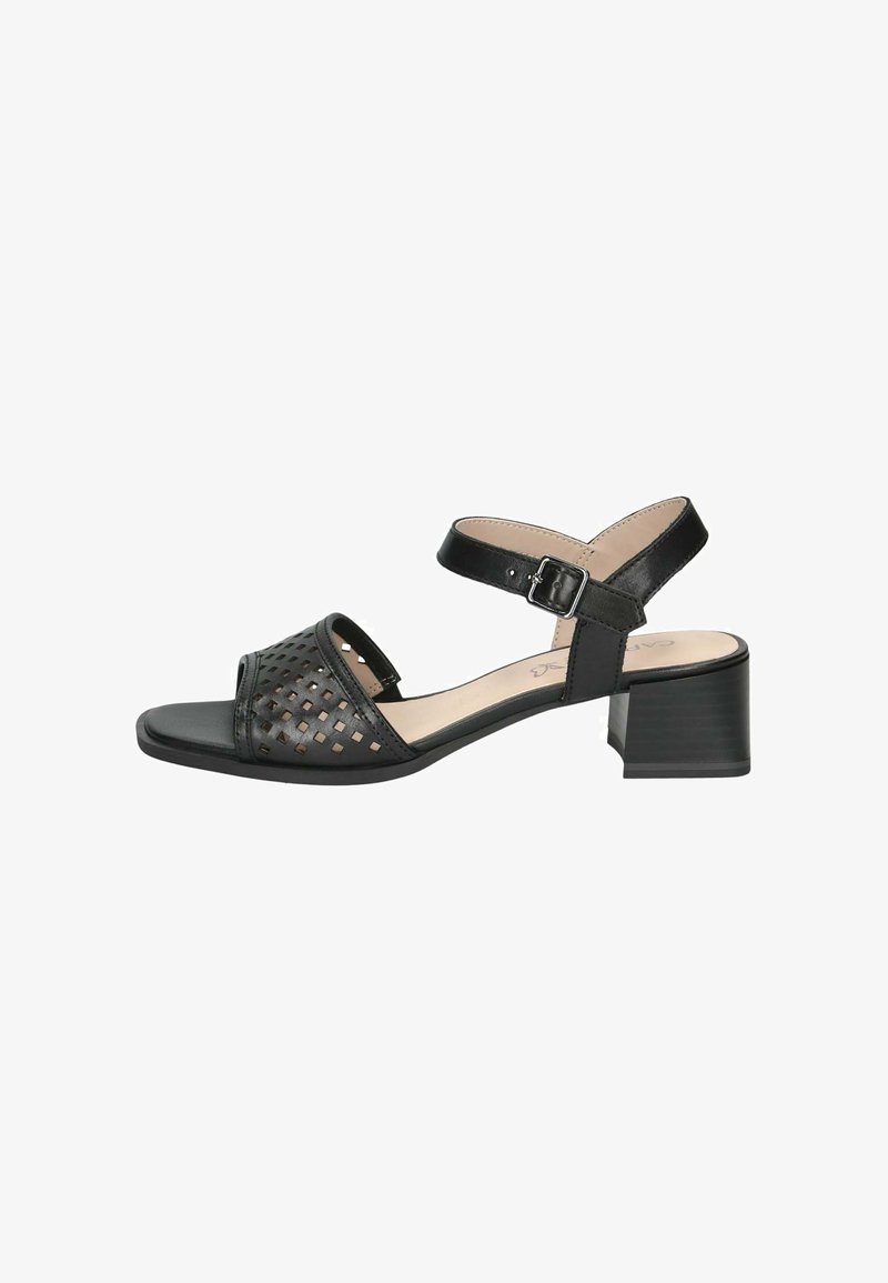 Sandale noire avec un design perforé comprenant des motifs découpés, un bout carré, un talon bloc et une bride de cheville réglable.