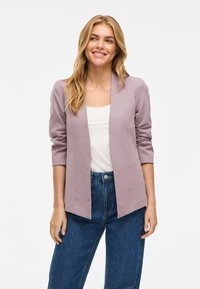 Blazer de color lavanda claro con un corte relajado y mangas de tres cuartos, que presenta una textura suave y un diseño de frente abierto, combinado con jeans azules.
