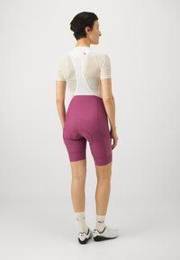 Lilla sykkelshorts med polstret sete, hvit topp i mesh og flate sømmer. Reflekterende detaljer og en kroppsnær design for komfort.