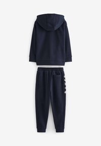 Marinblå hoodie med dragsko och långa ärmar, kombinerad med matchande byxor som har elastisk midja och sidficka, med "RAKER" tryckt.