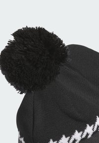 Cappello di maglia nera con una grande pompon nera sopra, caratterizzato da un motivo a zigzag bianco lungo il bordo inferiore. Texture morbida e vestibilità aderente.