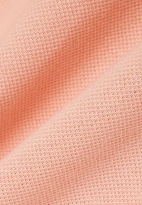Zacht roze stof met een gestructureerd, ademend breipatroon, met zachte plooien en een glad oppervlak.