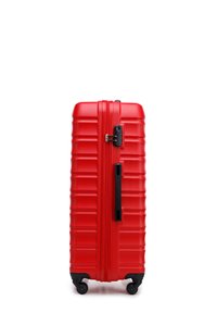 Valise rigide rouge avec un design à nervures, fermeture éclair centrale, poignée latérale et quatre roues pivotantes pour la mobilité. Texture lisse et matériau durable.