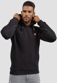 Zwarte textuur hoodie met een capuchon, voorzien van trekkoorden en een klein logo accent. Geribde manchetten en onderrand. Slim fit met een kangoeroezak.