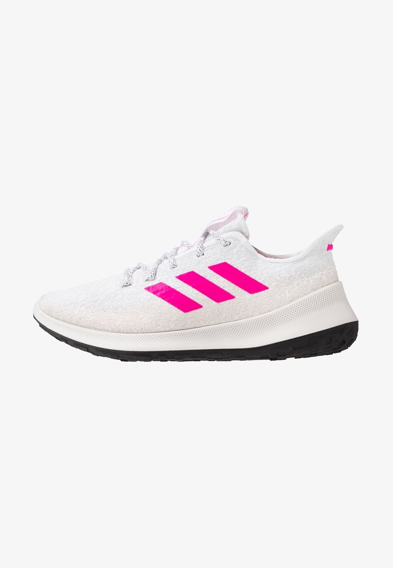 Chaussure de sport blanche avec logo rose à trois bandes, lacets blancs et semelle en caoutchouc noire, vue de côté sur fond blanc.