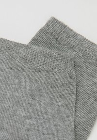 Calzini in cotone grigio con texture a coste e bordo elastico, caratterizzati da un design a maglia liscia. Il tessuto appare morbido e leggero.