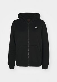 Sudadera negra con cremallera hecha de una mezcla de algodón. Presenta una capucha, bolsillos frontales y un logo Jumpman blanco en el pecho. Textura suave.