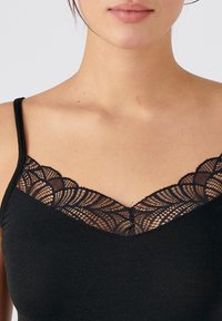 Black camisole with lace trim along the neckline, featuring a scalloped design and a central decorative button detail.
