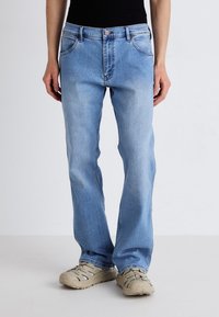 Jeans en denim bleu clair avec une coupe droite, cinq poches et une légère décoloration. Comprend une fermeture à bouton et des passants de ceinture.