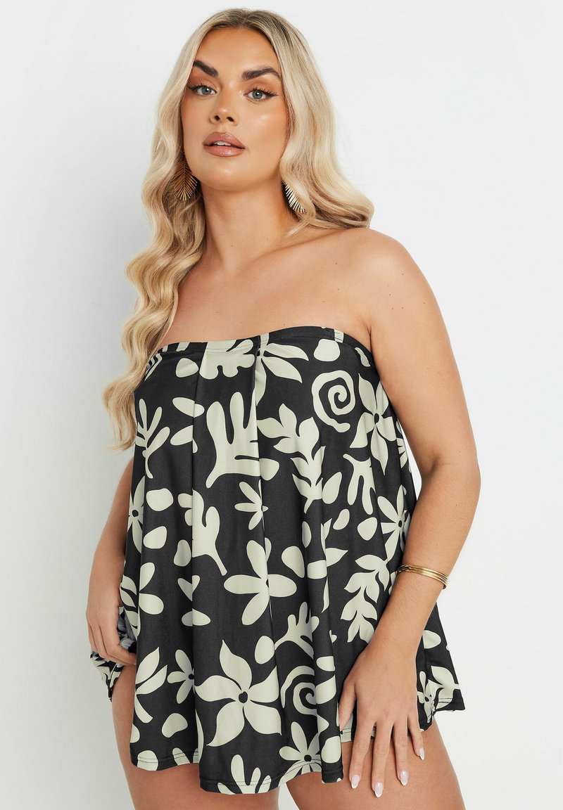 Utan axelband svart topp med ljusgröna blommor och virvelmönster. Har veck, en lös passform och en slät textur.