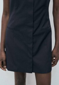 Dark gray pinstriped dress with two front pockets, tailored design, short length, and a vertical seam down the center. Smooth texture.
