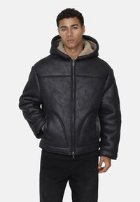  giacca nera in pelle con cappuccio e motivo trapuntato, chiusura con zip e rivestimento in shearling beige. Presenta tasche frontali e una vestibilità comoda.
