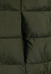 Tissu de doudoune vert olive avec une texture matelassée, présentant des sections horizontales, des coutures contrastantes et une surface lisse et brillante.