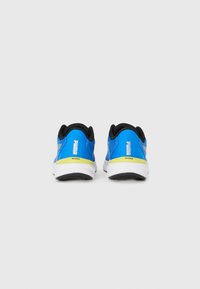 Une paire de chaussures de course Puma Nitro bleues vues de l'arrière, avec des semelles blanches et des accents jaunes.