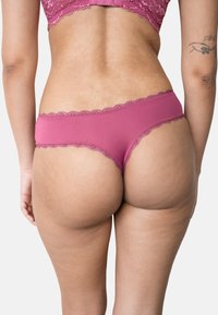 Rosa Spitzenbesetzte Slips, die eine weiche Textur und ein niedrig geschnittenes Design aufweisen. Detaillierte Spitze am Bundrand sorgt für visuelle Auflockerung.