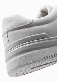 Weißer Sneaker mit einem strukturierten Wildleder-Obermaterial, glatten Überzügen und einer Gummisohle mit einem gemusterten Profil. Dezentes Logodetail an der Ferse.
