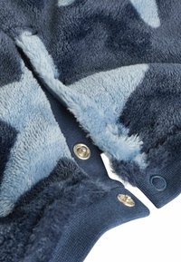 Fuzzy niebieski i granatowy polarowy materiał z wzorem gwiazd; posiada metalowe zatrzaski i miękką teksturę, z granatowym ściągaczem.