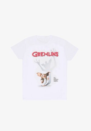 Witte katoenen t-shirt met een afbeelding van een klein wezen met grote oren en een speelse uitdrukking, vergezeld door de tekst "Gremlins" en beschrijvingen.