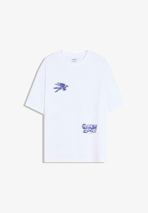 Bílé tričko s krátkým rukávem a modrým motivem ptáka na levé kapse a modrým nápisem „MOVING MY OWN WAY“ u pravého dolního okraje.