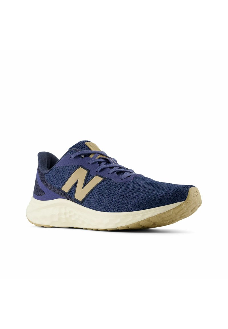 Chaussure de course en maille marine avec un logo "N" doré, semelle texturée, col rembourré et design à lacets. Matériau léger et respirant.