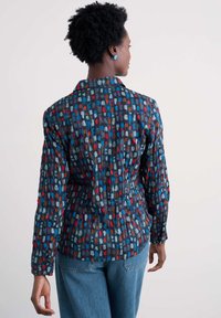 Koszula z długim rękawem, zapinana na guziki, zdobiona kolorowym, abstrakcyjnym wzorem w odcieniach niebieskiego, czerwonego i brązowego na ciemnym tle. Lekka, strukturalna tkanina.