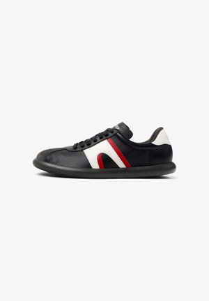 Black leather sneaker with white and red accents, rounded toe, textured upper, flat black sole, and lace-up design.