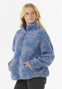 Veste en polaire bleue avec un col haut, fermeture éclair, poches latérales et motif texturé. Matériau doux et pelucheux, offrant une coupe décontractée.
