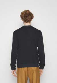 Felpa girocollo blu navy con maniche lunghe, polsini e orlo a coste, realizzata in morbido misto cotone. Il design posteriore è semplice, senza motivi visibili.