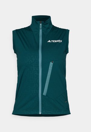 Gilet sans manches en teal avec col haut, fermeture éclair à l'avant et une poche zippée. Présente un motif géométrique sur le côté gauche et des coutures contrastées.