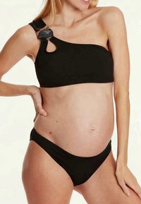 Top de bikini preto com design de um ombro e detalhe em metal circular, combinado com uma parte de baixo de cintura baixa correspondente.