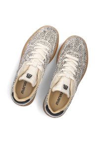 Witte sneakers met zwart gespikkeld patroon, vetersluiting, rubberen zool en tan accenten. Heeft een logo op de hiel en de binnenzolen.