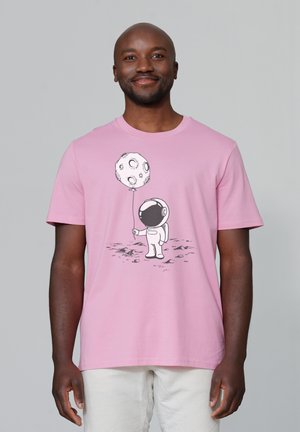 Rosa Baumwoll-T-Shirt mit einem schwarzen Grafikdesign eines Astronauten, der einen Mondballon hält, vor einem schlichten Hintergrund. Kurzarm, klassischer Schnitt.