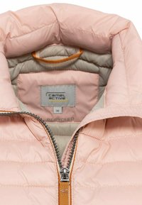 Pinker gepolsterter Mantel mit hohem Kragen, ausgestattet mit einem silbernen Reißverschluss und orangefarbenen Akzenten. Innenfutter in Beige mit einem Etikett, das auf recycelte Materialien hinweist.