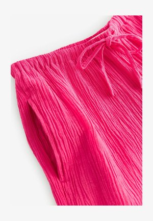 Pink textured pants with an elastic waistband and a drawstring. Features vertical ribbed lines and side pockets. Soft fabric material.
