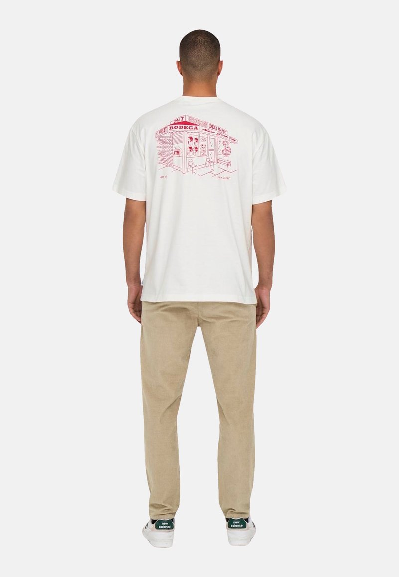 Weißes Baumwoll-T-Shirt mit einer roten Illustration eines Bodegas auf dem Rücken. Kurze Ärmel, lockere Passform, schlichte Vorderseite. Getragen mit hellbeigen Hosen.