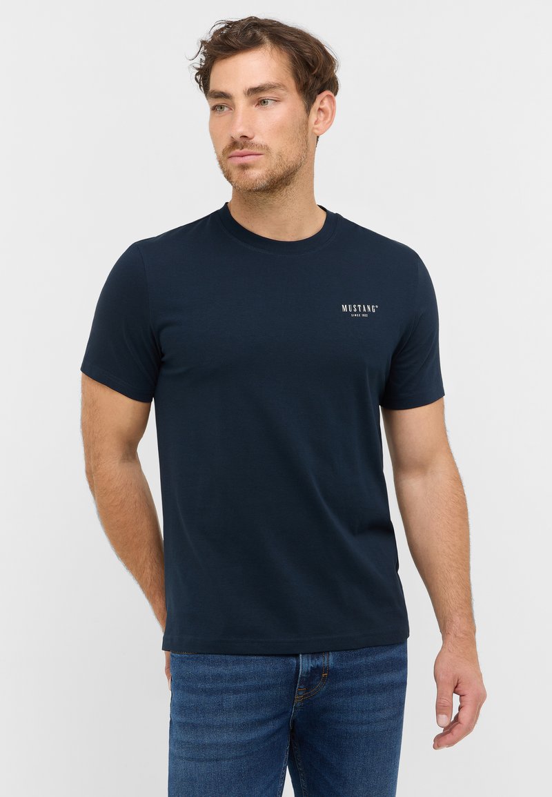 T-shirt en coton navy avec un col rond, des manches courtes et un petit logo blanc "MUSTANG" sur la poitrine. Texture douce, coupe régulière.