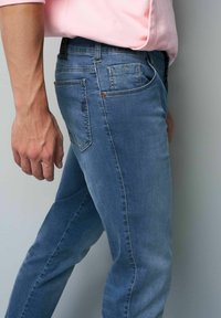 Heren blauwe denim jeans met een slim fit, voorzien van zichtbare stiksels, vijf-pocket ontwerp en een lichte vervaging op de stof.