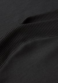 Sweatshirt noir avec un col et un ourlet côtelés, texture lisse et design épuré avec des détails de couture minimalistes.