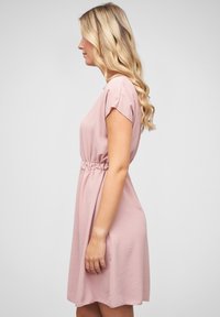 Pink short dress with a relaxed fit, cap sleeves, cinched waist, and a subtle texture. Hemline falls above the knee. Simple and clean design.