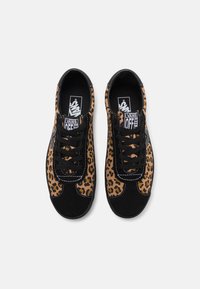 Baskets en toile imprimé léopard avec des accents en suède noir, des lacets noirs et des détails de couture blanche. Vue de dessus de deux chaussures.