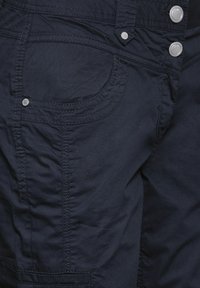 Marinblå cargo shorts gjorda av lättviktsmaterial med synlig sömnad, två framfickor och silverfärgade metallknappdetaljer.