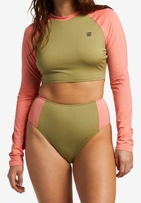 Leichtes Zweiteiler-Badeanzug-Set mit einem grünen, langärmeligen Crop-Top mit rosa Akzenten und hochgeschnittenen Bikini-Shorts in passenden Farben.