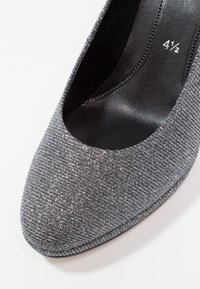 Gros plan sur une chaussure de soirée pour femme grise pailletée, taille 4½, avec un bout arrondi et une doublure intérieure noire.